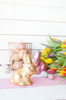 Lots of colorful Easter bunnies made of chocolate and fresh tulips