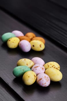 Mini Easter eggs on a modern dark wooden floor. Flower pattern with copy space.