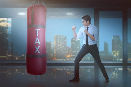 Powerful asian businessman puncing boxing heavy bag with tax sign on it in the office