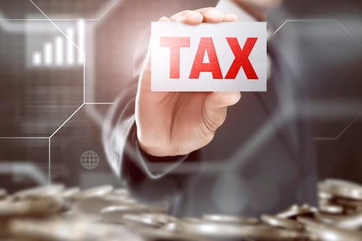 Businessman showing a card with Tax sign on coins pile background