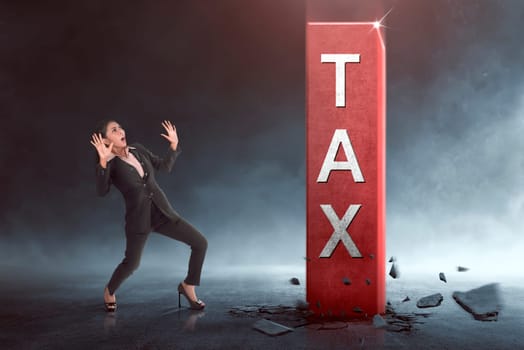 Surprised asian business woman with tax block coming out from the ground on black background