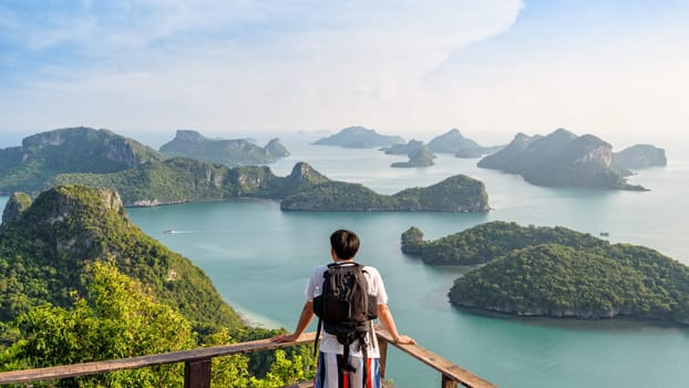 Man tourist with backpack are looking at the beautiful natural landscape of the sea on peak view point of Ko Wua Ta Lap island in Mu Ko Ang Thong National Park, Surat Thani, Thailand, 16:9 Widescreen