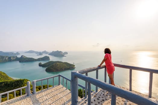 Woman tourist on the podium is peak view point of Ko Wua Ta Lap island and beautiful nature landscape during sunrise over the sea in Mu Ko Ang Thong National Park, Surat Thani, Thailand