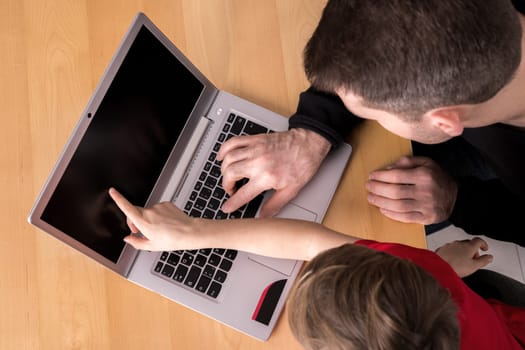 father and son using computer togetherat home