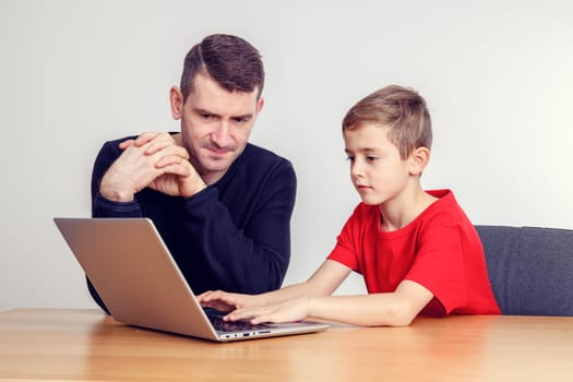 father and son using computer togetherat home