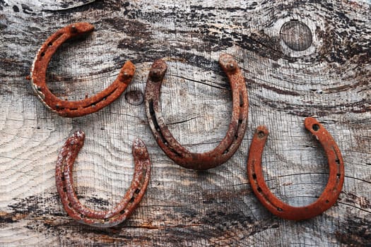 Four old rusty horseshoes on a wooden surface. Horseshoes as lucky charms