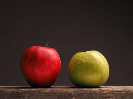 One green apple and one red apple on a rustic wooden table with place for text