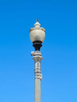A tall lamp post with blue sky behind
