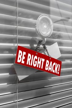 A sign saying "be right back"" on a glass door with a white, closed venetian blind. It can be used for business concepts or backgrounds."