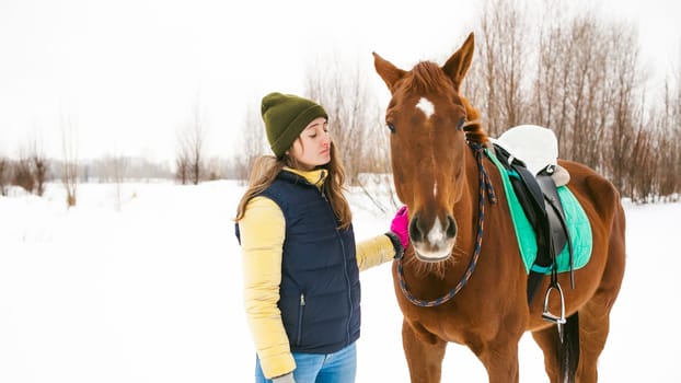 Woman in winter clothes and the horse stand together against the white snow. love and care for horses. animal portrait on a white background.