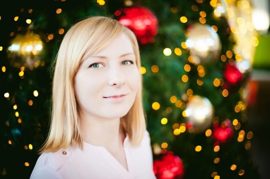 portrait of a young blonde woman on a background decorated Christmas tree in blur