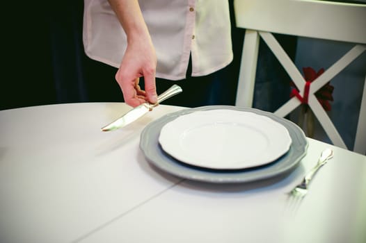 blonde woman housewife doing the work in the kitchen, setting the table, puts the dishes and cutlery. home in the kitchen in a bright interior