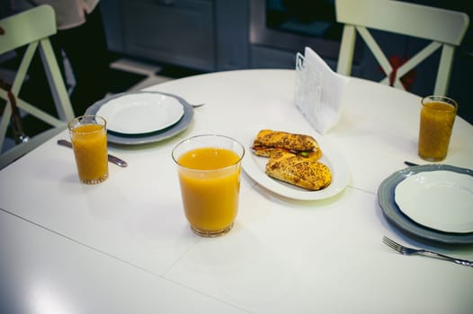 breakfast sandwich and peach juice. on the table in the bright interior of the kitchen in a plate is a sandwich juice poured in a glass