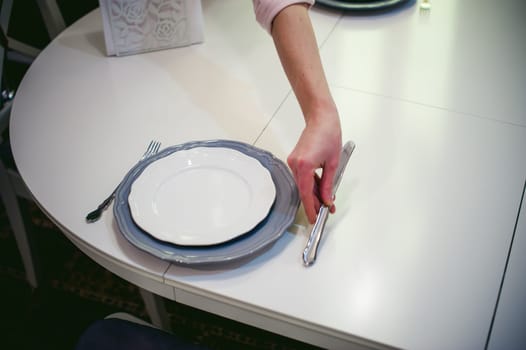 blonde woman housewife doing the work in the kitchen, setting the table, puts the dishes and cutlery. home in the kitchen in a bright interior