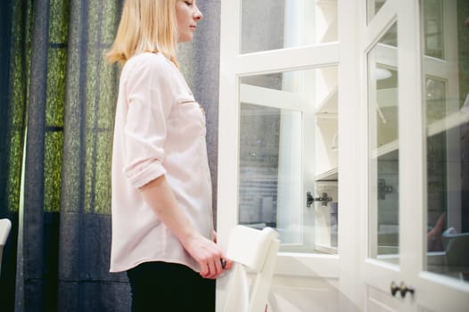 woman housewife in the kitchen. girl pulls out from the shelf cupboard dishes for table service.