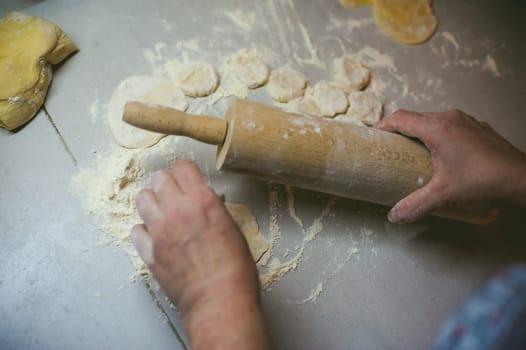 hand modeling dumplings at home in the kitchen. rolling pin in hand rolls dough