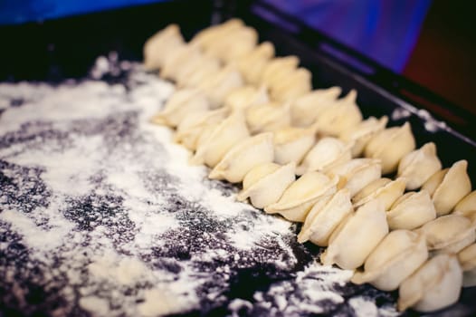 hand modeling dumplings at home in the kitchen. pelmeni lay on a baking sheet
