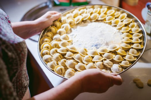 hand modeling dumplings at home in the kitchen. pelmeni lay on a baking sheet