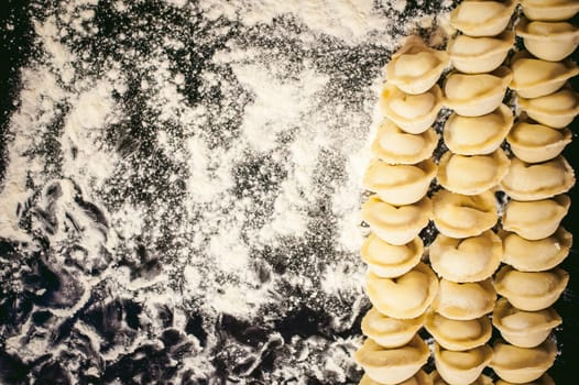 hand modeling dumplings at home in the kitchen. pelmeni lay on a baking sheet