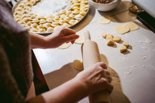 hand modeling dumplings at home in the kitchen. pelmeni lay on a baking sheet