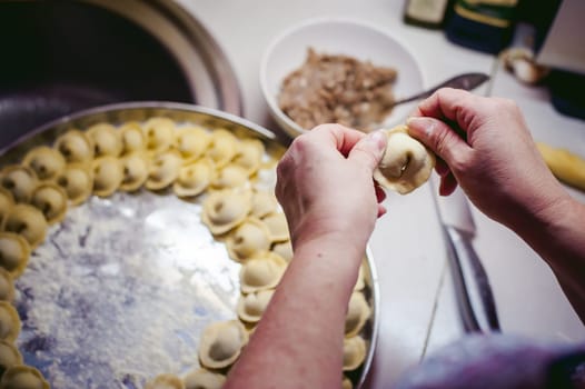 hand modeling dumplings at home in the kitchen.