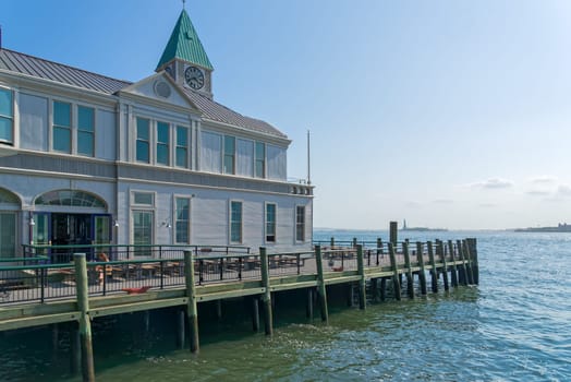 New York, NY, USA - June 06, 2015: Pier A Harbor House with restaurant situated on the Hudson River at Battery Park, Lower Manhattan. Modern skyscrapers in the background. Blue sky.