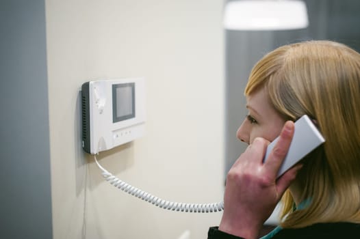blonde woman answers the intercom call while holding the phone to your ear