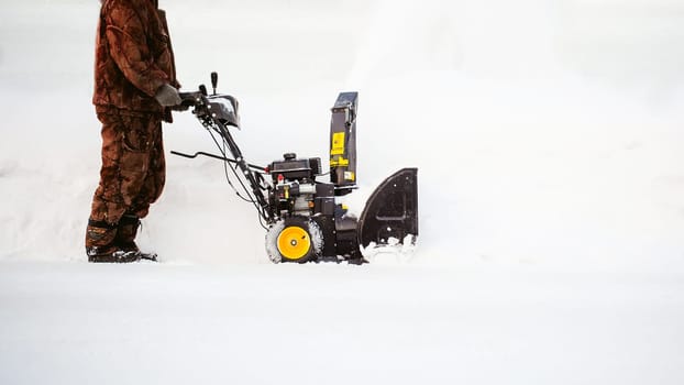 man operating snow blower to remove snow on driveway