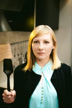 blonde woman in the kitchen, holding a cutlery
