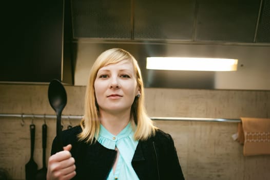blonde woman in the kitchen, holding a cutlery
