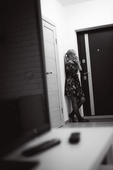 blonde woman answers the intercom call, hold the phone to his ear, waiting for the arrival of the long-awaited guest. Being in apartment near front door