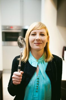blonde woman in the kitchen, holding a cutlery