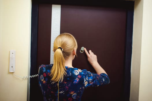 blonde woman answers the intercom call, hold the phone to his ear, waiting for the arrival of the long-awaited guest. Being in apartment near front door
