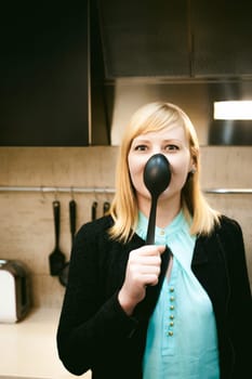 blonde woman in the kitchen, holding a cutlery