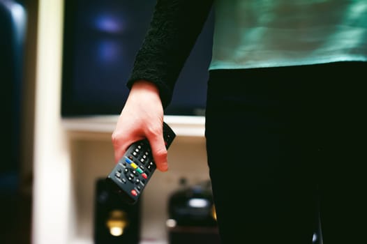 girl in a home environment, holding a TV remote, switching channels
