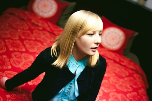 blonde woman sitting resting on the couch in the living room at home.