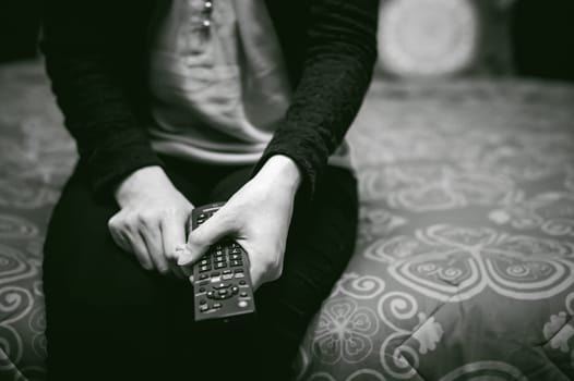 girl in a home environment, holding a TV remote, switching channels