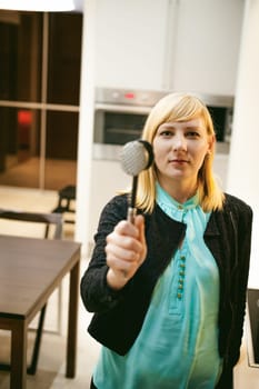 blonde woman in the kitchen, holding a cutlery