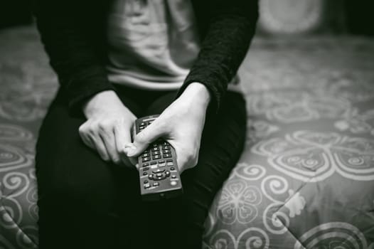 girl in a home environment, holding a TV remote, switching channels