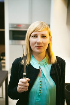 blonde woman in the kitchen, holding a cutlery
