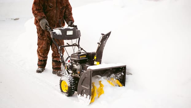 man operating snow blower to remove snow on driveway