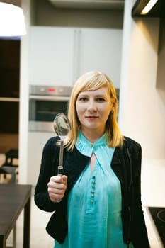 blonde woman in the kitchen, holding a cutlery