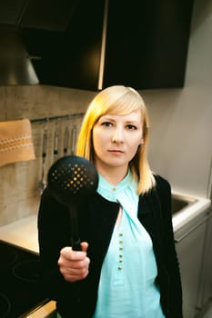blonde woman in the kitchen, holding a cutlery