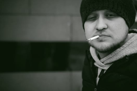 Portrait of a man with a beard with a mustache, smoking a cigarette, with an emotional face in the open air