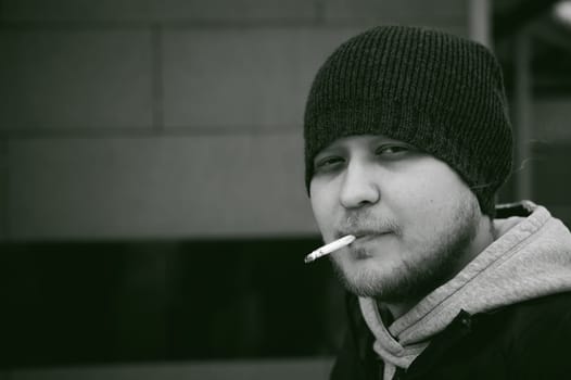 Portrait of a man with a beard with a mustache, smoking a cigarette, with an emotional face in the open air