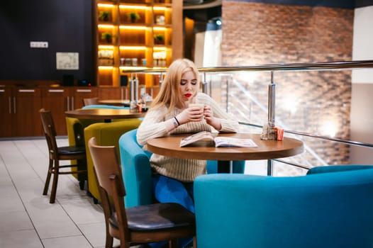 Picture of young lady sitting in cafe while reading magazine And drinks coffee