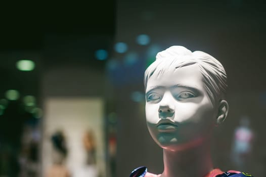 dummy on a shop window. Child face in the background of the store