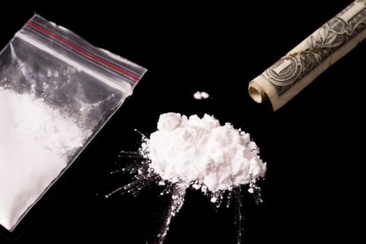 cocaine, Herion or other illegal drugs that are sniffed by means of a tube or injected with a syringe and money, isolated on black glossy background