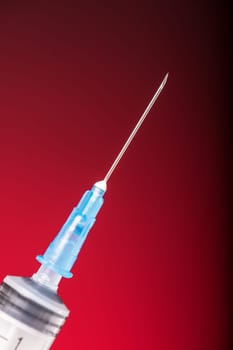 Isolated medical syringe on red, dark background