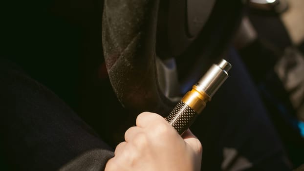young vaper man with beard vaping mechanical mod. Guy smokes an electronic cigarette by blowing a smoke vapor. Holds in hand Sitting at the wheel of a car  background
